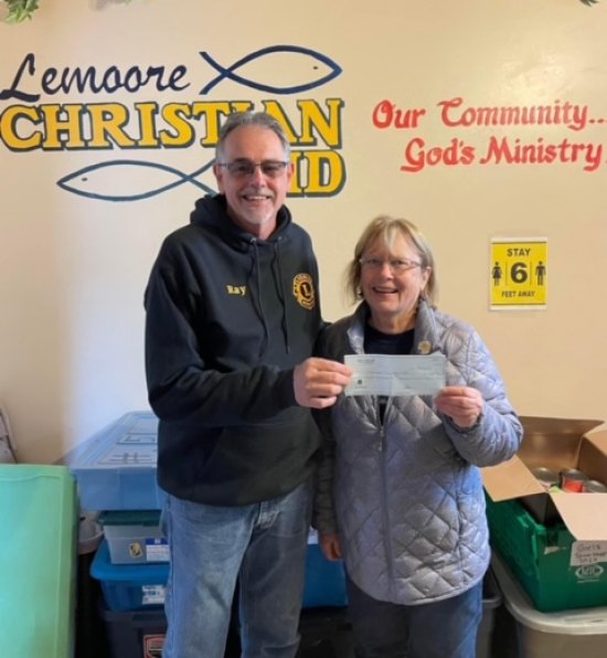Kings Lions Club delivers early Christian gift of $1,000 to local Lemoore Christian Aid Kings Lions Club's Ray Etchegoin awards a $1,000 check to Karen Christensen of Lemoore Christian Aid.